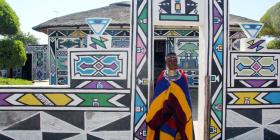 L'artiste Esther Mahlangu devant une maison peinte
